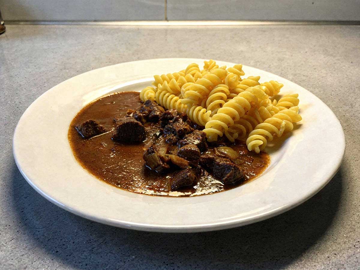 Een bord met fusilli en rundergoulash met chocolade.