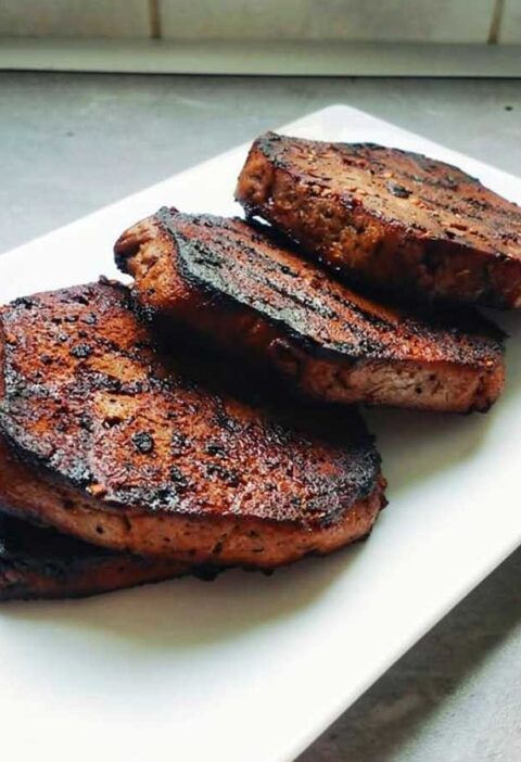 4 gebakken vegan biefstukken op een witte schaal.