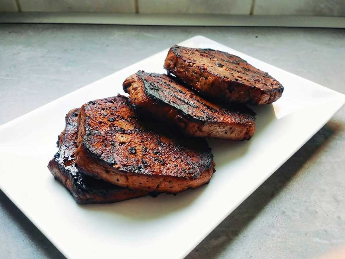 4 gebakken vegan biefstukken op een witte schaal.