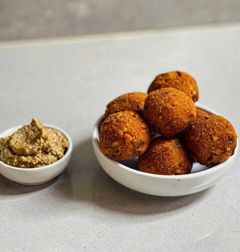 Een schaaltje met gefrituurde bitterballen en een schaaltje met grove mosterd.