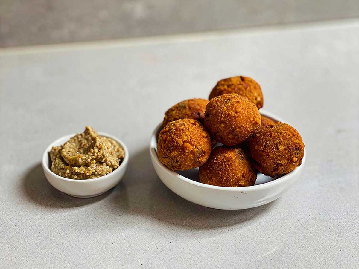 Een schaaltje met gefrituurde bitterballen en een schaaltje met grove mosterd.