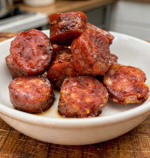 Dikke plakken gebakken chorizo met een krokant randje in een wit schaaltje.