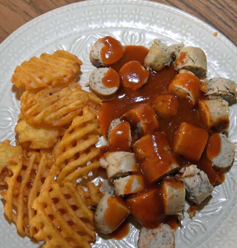 Duitse curryworst met wafelpatat op een bord in mijn eigen keuken. Heerlijk!