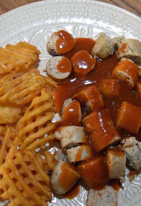 Duitse curryworst met wafelpatat op een bord in mijn eigen keuken. Heerlijk!