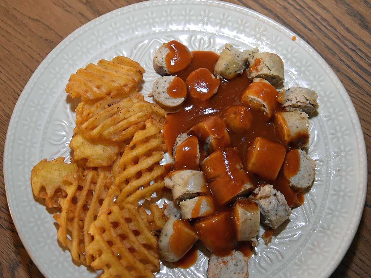 Duitse curryworst met wafelpatat op een bord in mijn eigen keuken. Heerlijk!