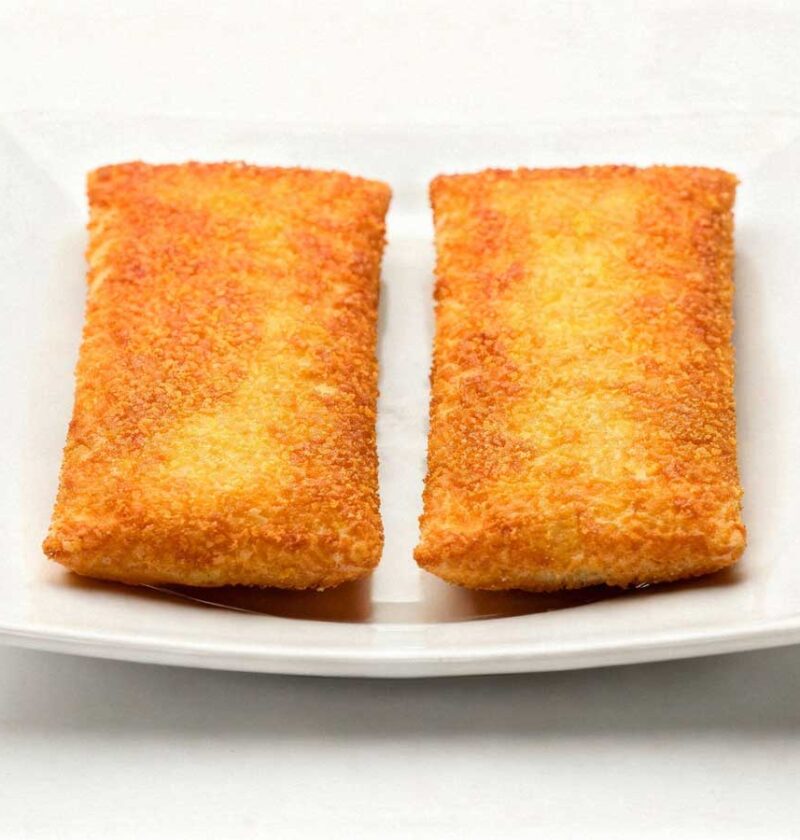 Twee goudbruin gebakken kaassoufflés op een vierkant wit bord onder helder studiolicht.
