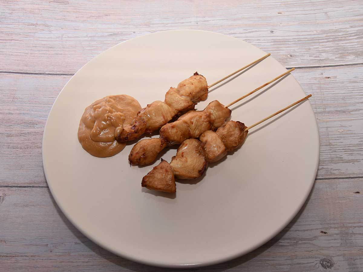 3 gebakken kipsaté op een bord, met zelfgemaakte pindasaus.