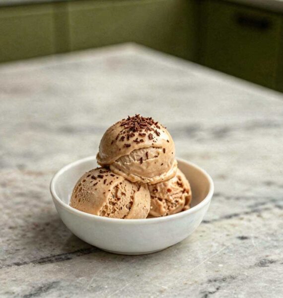 Drie bollen ambachtelijk koffie roomijs met chocoladeschaafsel in een wit schaaltje.