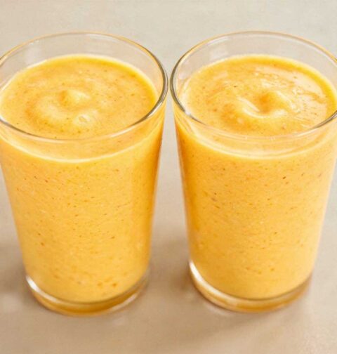 Twee tumblr glazen gevuld met romige, gele mango lassi.