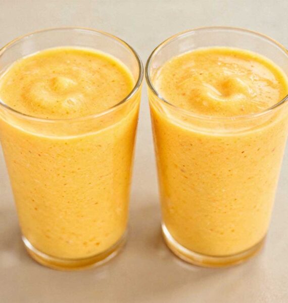 Twee tumblr glazen gevuld met romige, gele mango lassi.