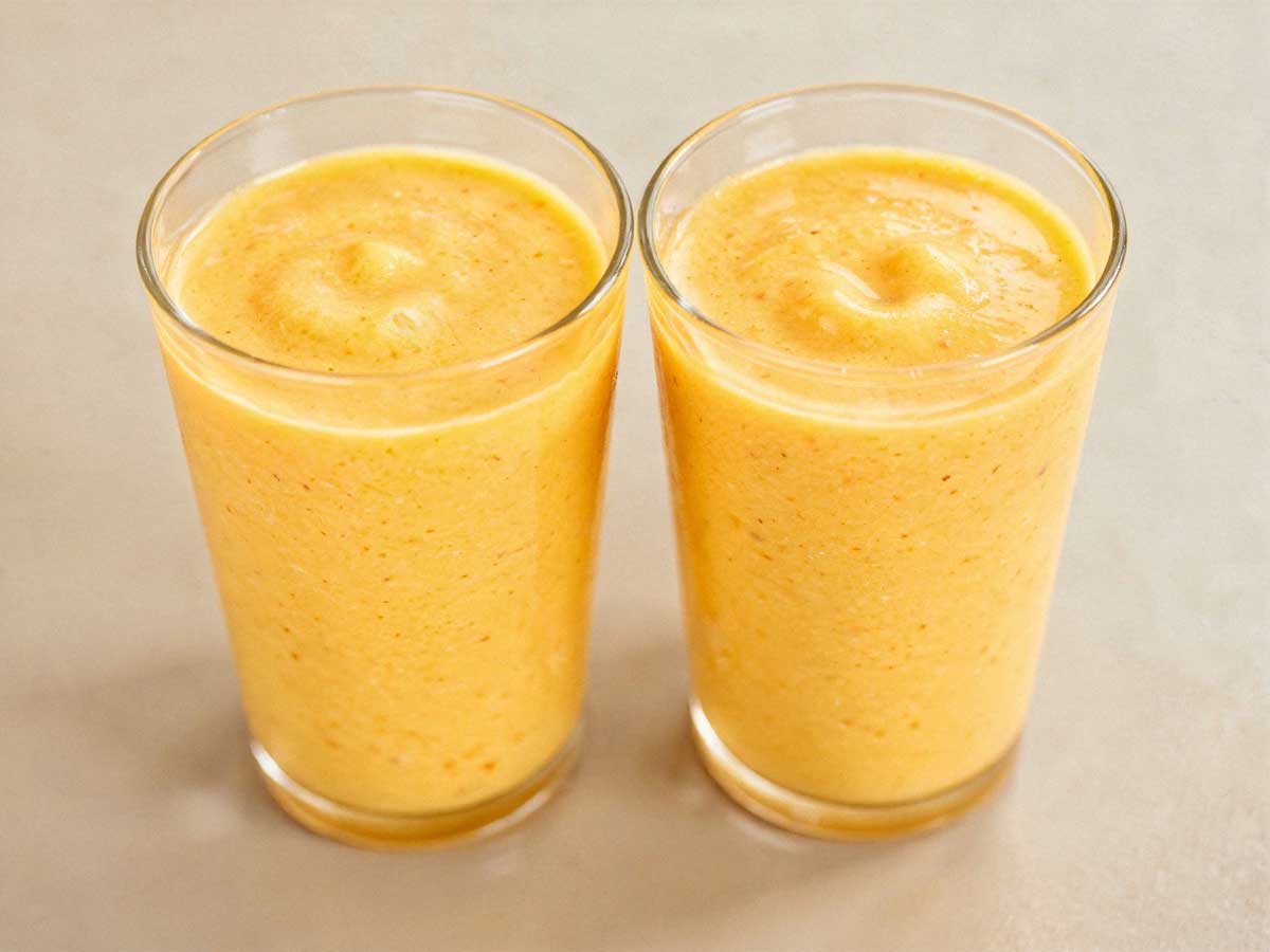 Twee tumblr glazen gevuld met romige, gele mango lassi.