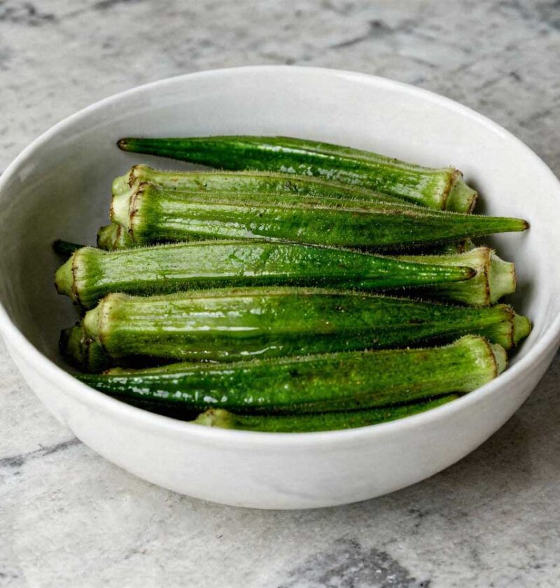 Een wit schaaltje gevuld met hele gekookte groene okra's.