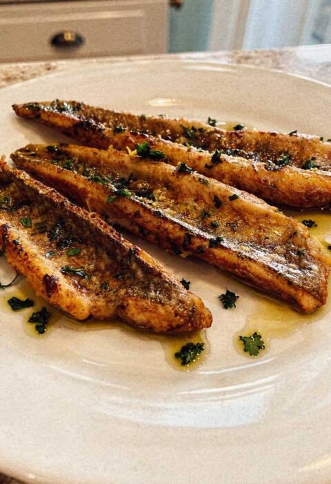 Drie gebakken pietermanfilets op een wit bord