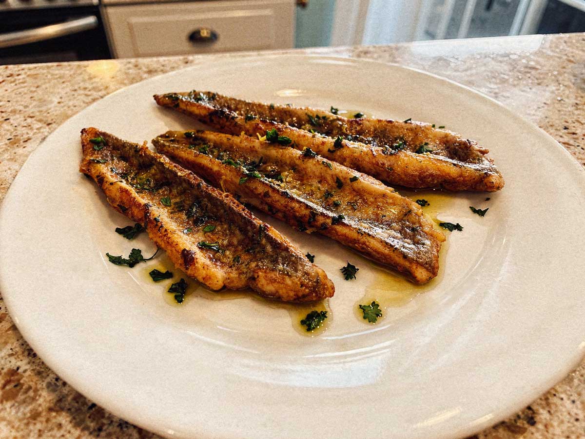 Drie gebakken pietermanfilets op een wit bord