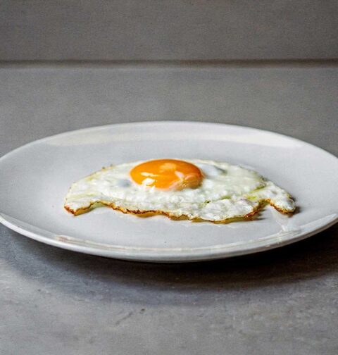 Een spiegelöei, perfect gebakken, op een wit bord.