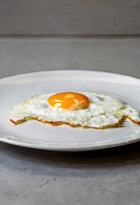 Een spiegelöei, perfect gebakken, op een wit bord.