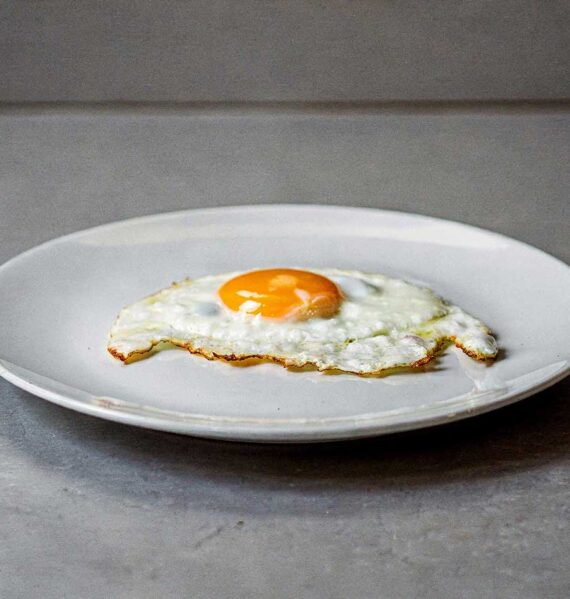 Een spiegelöei, perfect gebakken, op een wit bord.