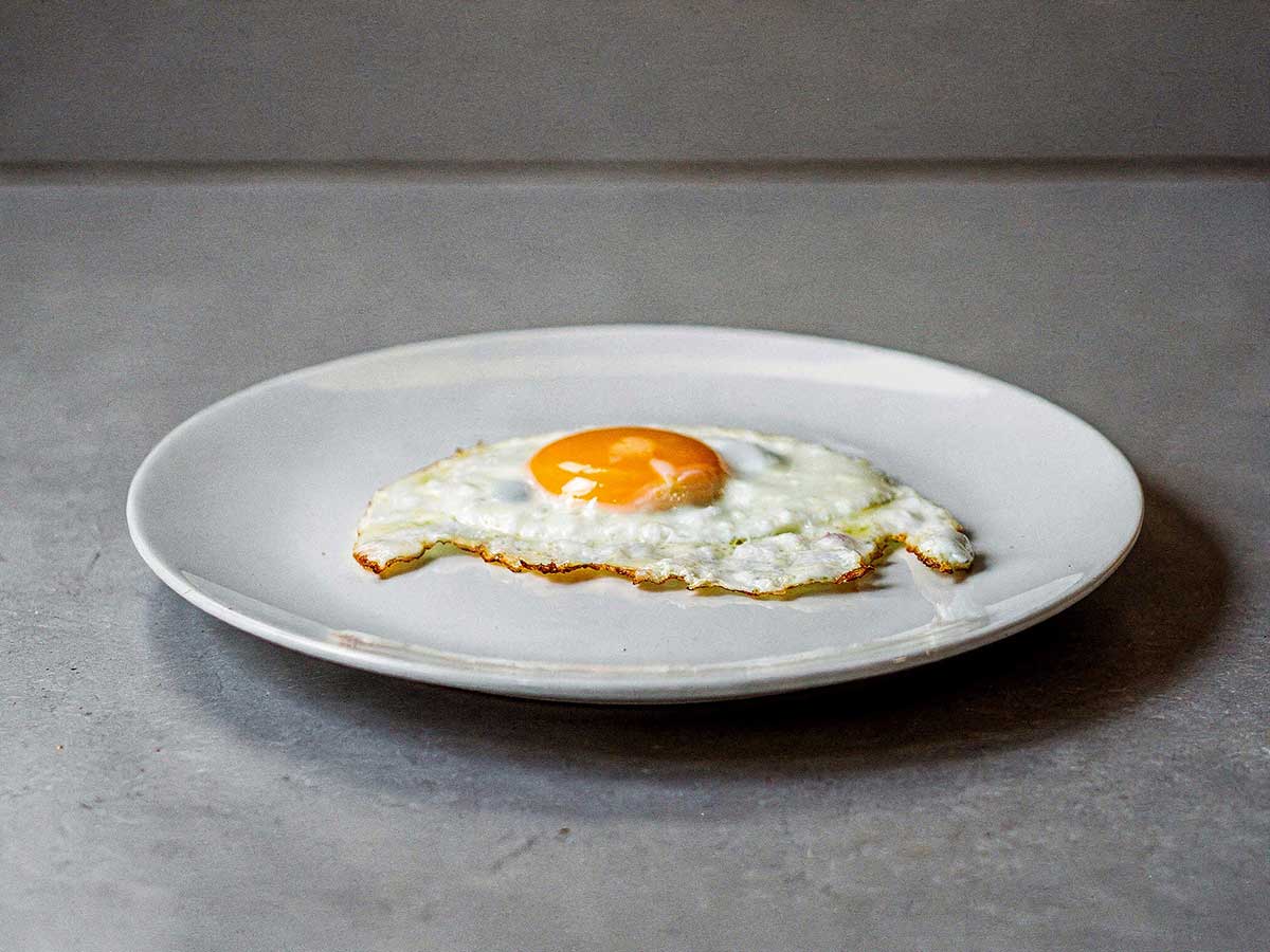 Een spiegelöei, perfect gebakken, op een wit bord.
