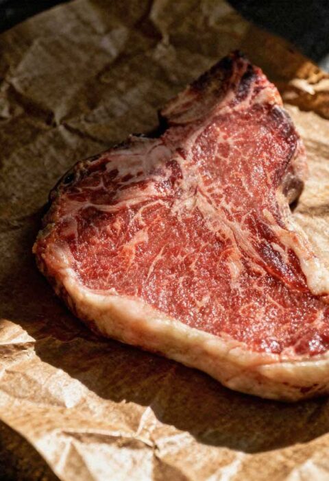 Een hele gebakken T-bone steak op slagerspapier.