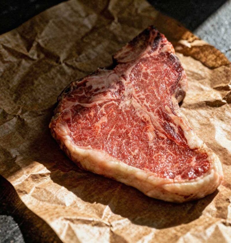 Een hele gebakken T-bone steak op slagerspapier.