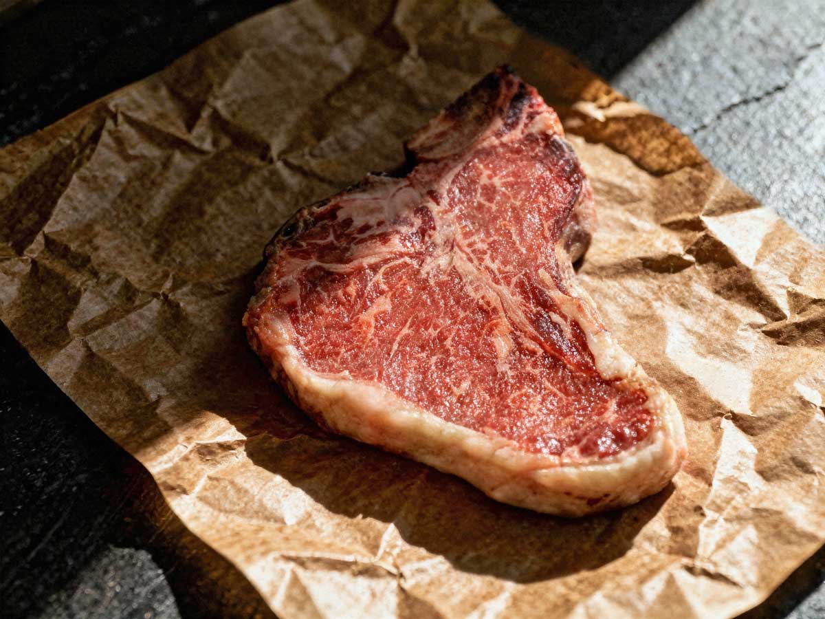 Een hele gebakken T-bone steak op slagerspapier.