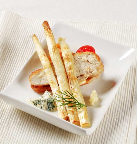 3 gebakken witte asperges op een bord met onder andere een stuk gebakken kip.