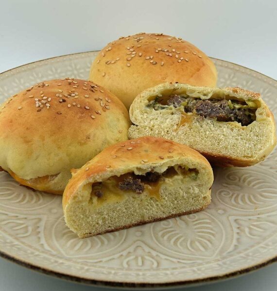 3 Cheeseburgers in een broodje, waarvan er 1 doormidden is gesneden zodat je de cheeseburger in het broodje kunt zien.