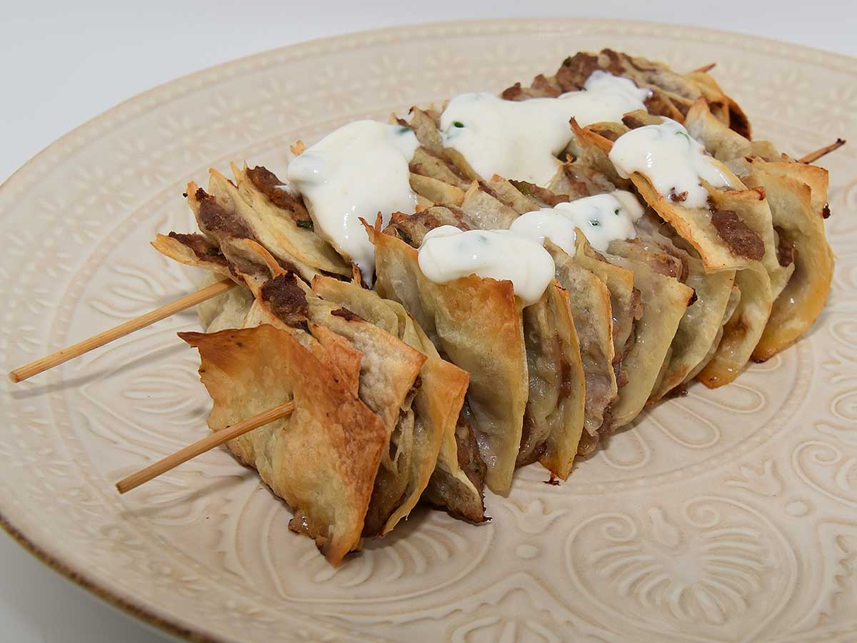 2 spiesjes met daarop vierkante stukjes wrap met daartussen gehakt.