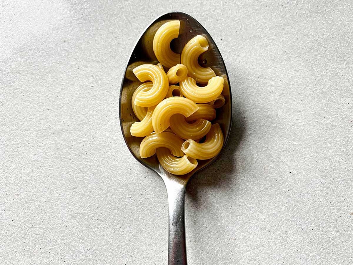 Een eetlepel met ongekookte macaroni, om aan te geven hoeveel een eetlepel eigenlijk is.