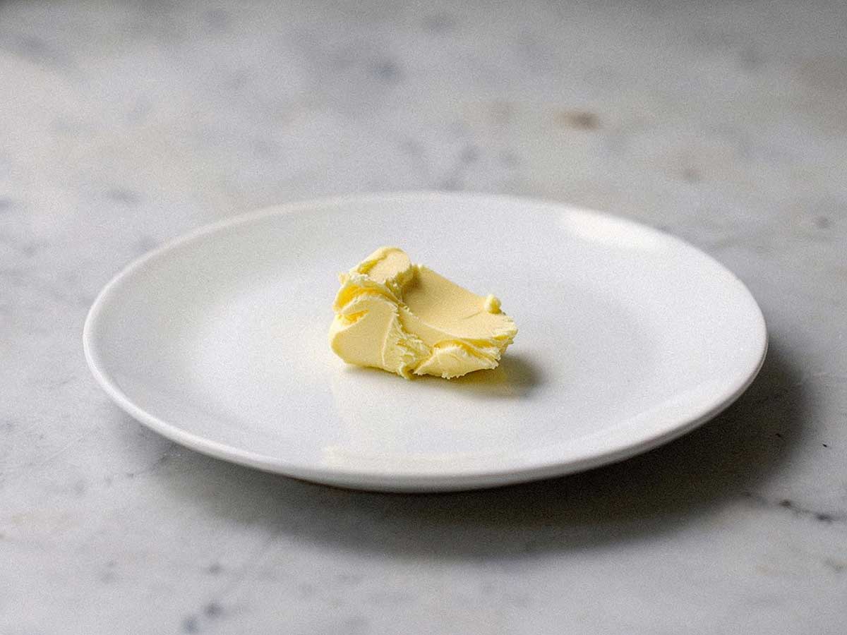 Een klont boter op een klein wit bordje.