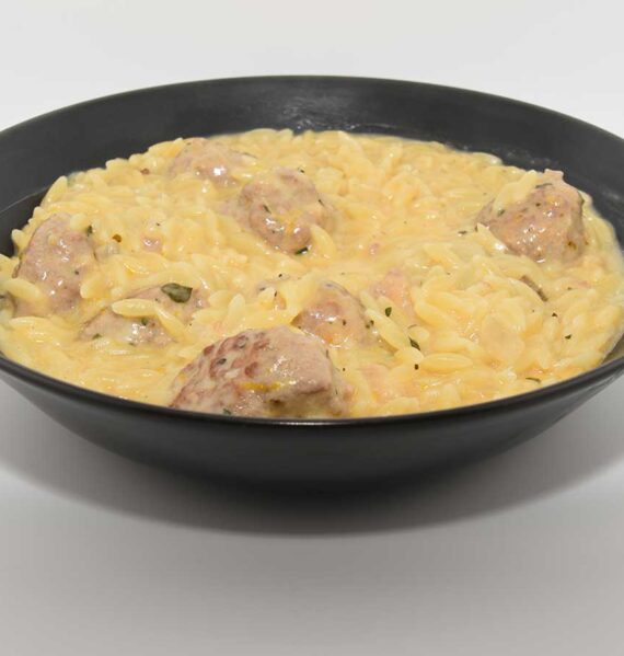 Een kom met een portie sinaasappelorzo met gekruide gehaktballetjes.